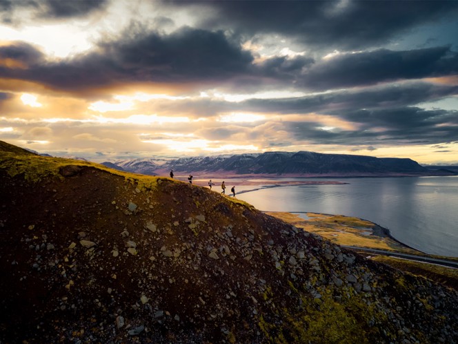 A group of hikers walking on a mountain ridge at dusk.